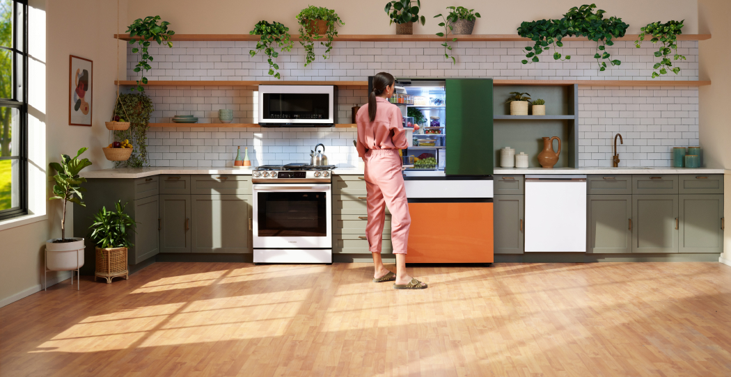 photo of a woman standing in a bright, colorful kitchenw ith matte white and orange appliances